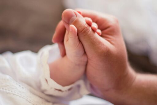 A dad holding hands with his baby